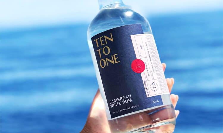 Ten To One White Bottle in hand over water