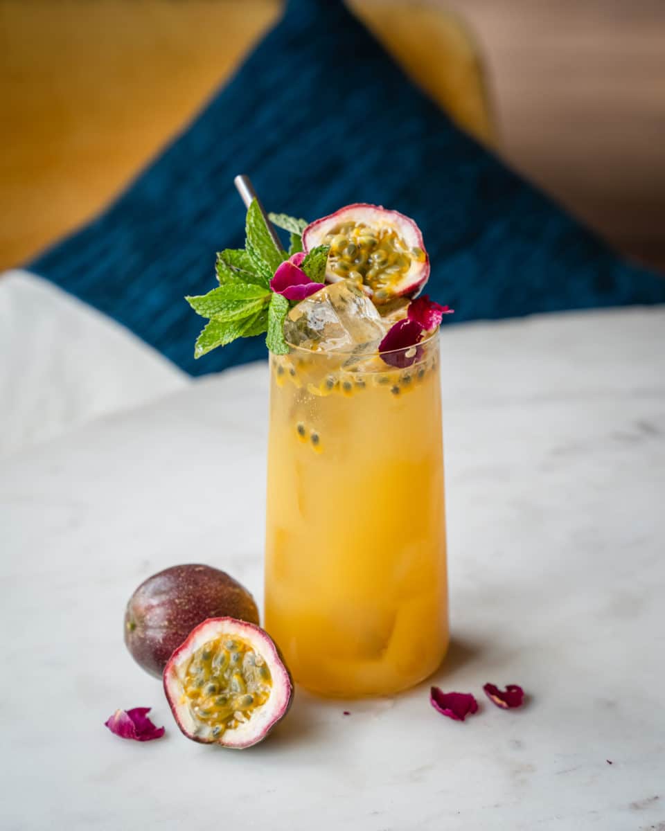 yellow mojito standing on a table fruit laying around it