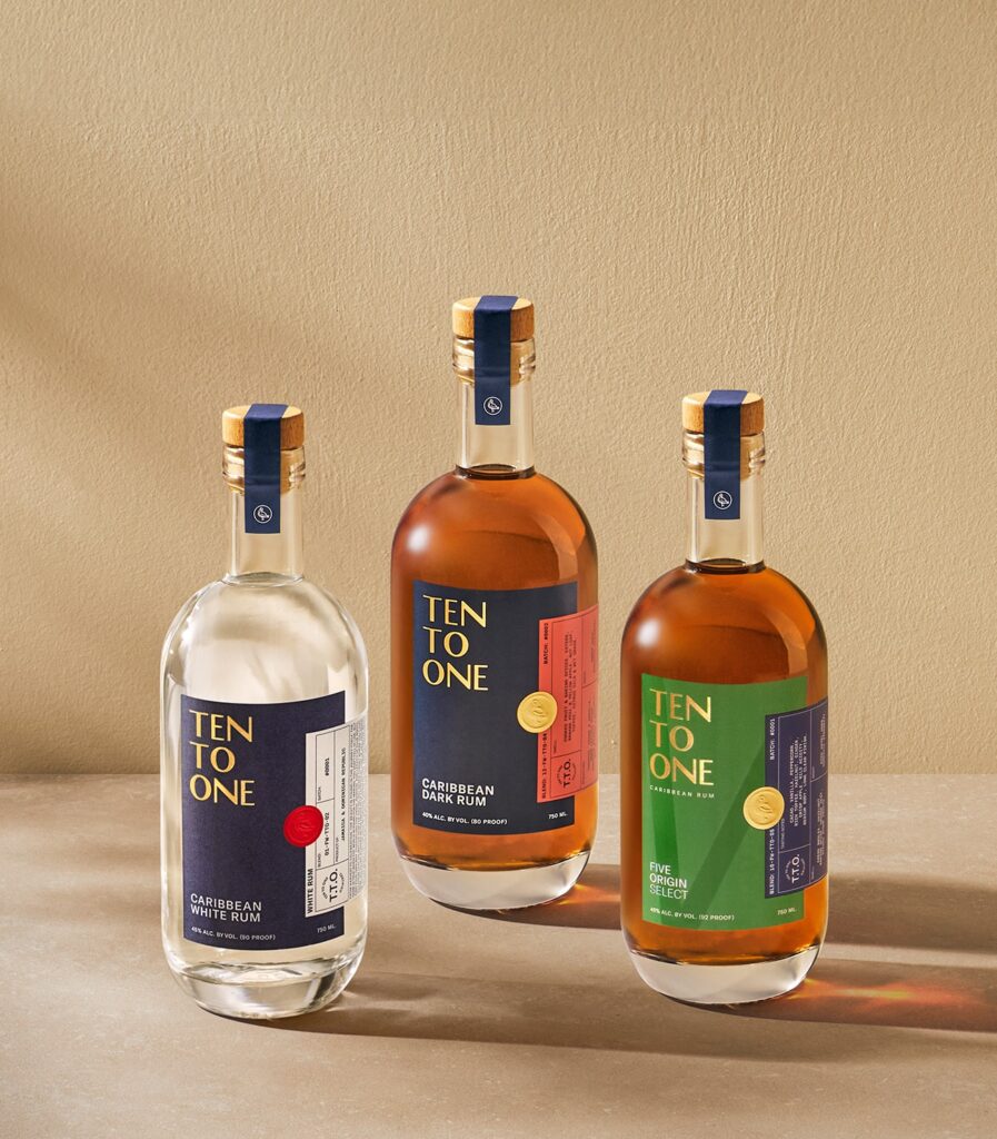 Three bottles of Ten To One Rum on a plain beige counter. From left to right: White Rum, Dark Rum, Five Origin Select.